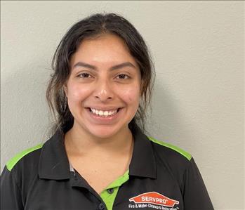 Female employee in black shirt standing in front of a green background.