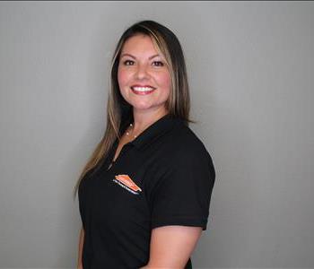 Female employee with brown hair smiling in front of a grey background.