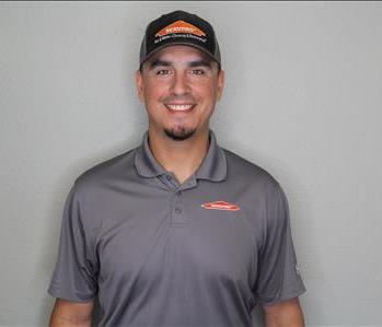 Male employee with brown hair smiling in front of a grey background.