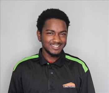 Male employee with brown hair smiling in front of a grey background.