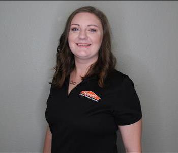 Female employee with red hair smiling in front of a grey background.