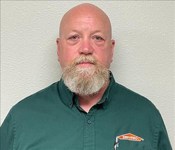 Male employee in a green shirt in front of a grey background.