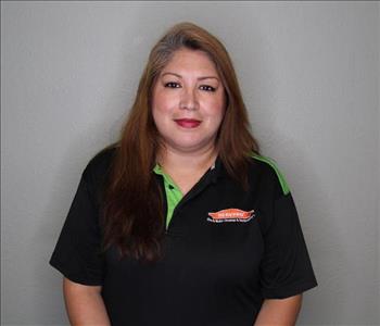 Female employee with brown hair smiling in front of a grey background.