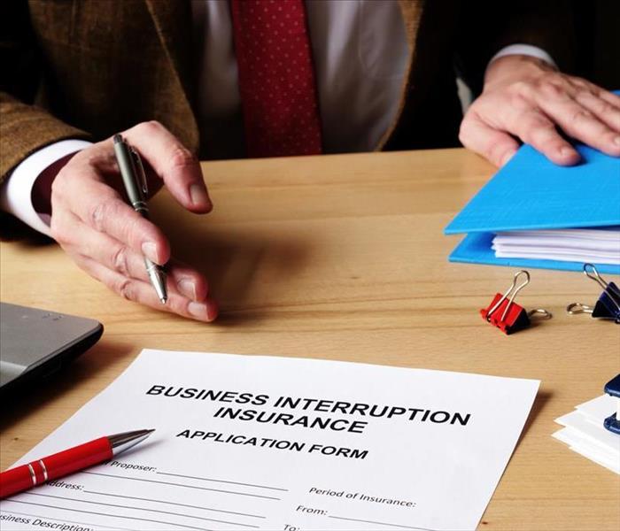 Business interruption insurance form and red pencil to sign.